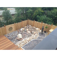 Ein naturfarbener Bambuszaun umgibt einen modern gestalteten Gartenbereich mit Kies und Steinplatten. Der Sichtschutz aus Bambus sorgt für Privatsphäre und fügt sich harmonisch in die natürliche Umgebung ein.