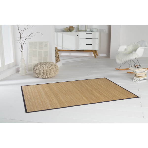 Ein modernes Wohnzimmer mit einem Bambusteppich HighQ 11mm Stege, der durch seine schmale, dunkle Bordüre und die natürliche Bambusoptik auffällt. Der Teppich ist in der Größe 90 x 160 cm und passt perfekt in den hellen, minimalistischen Raum.