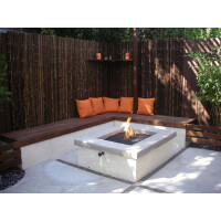 Gartenbereich mit modernem Sitzplatz und Feuerstelle, umgeben von einem dekorativen Bambus-Sichtschutz, der Privatsphäre und natürliche Eleganz bietet.