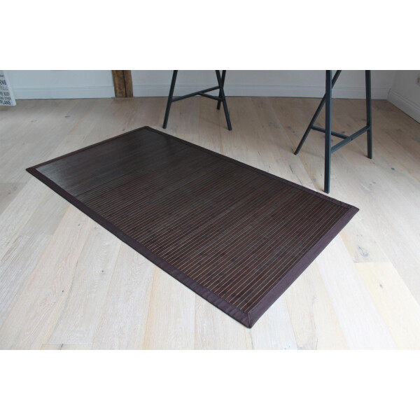 Großer Bambusteppich in dunkelbrauner Farbe mit breiter, abgesetzter Bordüre, der auf hellem Holzboden liegt. Der Teppich hat eine Größe von 200 x 250 cm und verleiht dem Raum eine natürliche, moderne Atmosphäre.