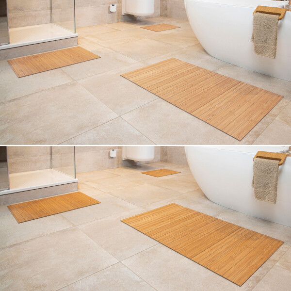 Drei Bambus Badematten in verschiedenen Größen, die vor einer Badewanne und einer Dusche auf einem gefliesten Badezimmerboden platziert sind. Die Matten bestehen aus hellbraunem Bambus mit klaren, parallelen Lamellen und bieten eine natürliche, stilvolle Optik.