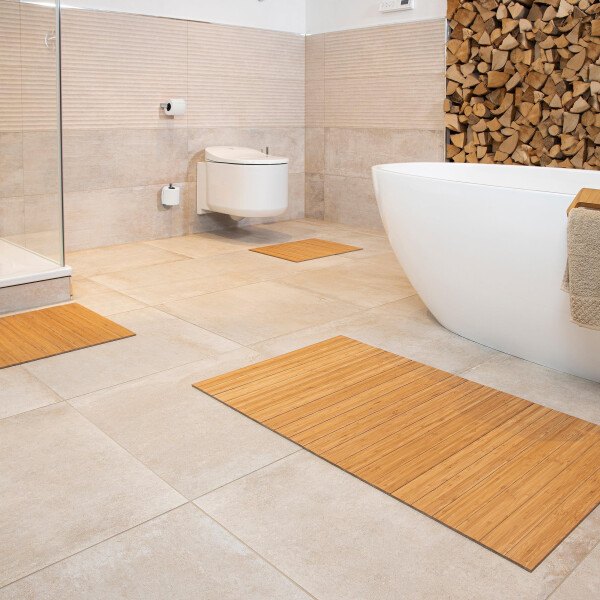 Moderner Badezimmerboden mit mehreren Bambus-Badematten in verschiedenen Größen, darunter die GRAND nature 40 x 50 cm. Die Matten sind aus natürlichem Bambus gefertigt und harmonieren mit der minimalistischen, hellen Einrichtung des Badezimmers.