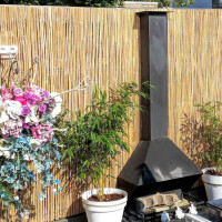 Bambussichtschutz Rollzaun CALAMA mit natürlicher Optik und einer Größe von 120 cm x 500 cm, der in einem Garten mit Pflanzen und Dekoration verwendet wird.