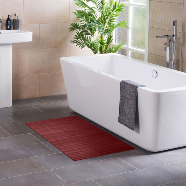 Moderner Badezimmerteppich LINES in Aurora aus Bambus, der stilvoll vor einer freistehenden Badewanne platziert ist. Der Teppich in kräftigem Rot bietet eine rutschfeste und wasserabweisende Oberfläche, ideal für den täglichen Gebrauch. Die geraden Linien des Designs verleihen dem Raum einen eleganten, minimalistischen Look.