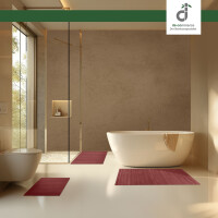 Modernes Badezimmer mit freistehender Badewanne, bodengleicher Glasdusche und warmen Naturtönen; drei unterschiedlich große, warm-rote Bambus-Badematten liegen jeweils davor, Tageslicht fällt durch ein großes Fenster, oben rechts das DE-COmmerce-Logo.