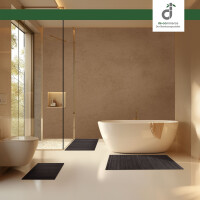 Modernes Badezimmer mit freistehender Badewanne, bodengleicher Glasdusche und warmen Naturtönen; drei unterschiedlich große, schwarzbraune Bambus-Badematten liegen jeweils davor, Tageslicht fällt durch ein großes Fenster, oben rechts das DE-COmmerce-Logo.