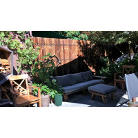 Sichtschutz aus Bambus in dunkler Farbe, der einen Gartenbereich mit Sitzmöbeln und Pflanzen umgibt, bietet natürliche Privatsphäre und ästhetische Akzente.