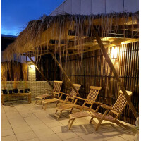 Stilvoller Außenbereich mit einem Sichtschutz aus Bambus, der Privatsphäre und natürliche Ästhetik bietet. Die Bambuswände schaffen eine tropische Atmosphäre, während die Holzliegen zum Entspannen einladen.