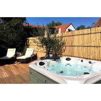 Moderner Bambus-Sichtschutzzaun in hellem Naturton, der einen gemütlichen Außenbereich mit Whirlpool und Liegestühlen einrahmt. Die Bambusstäbe sind dicht aneinandergereiht und bieten Privatsphäre, während sie gleichzeitig eine natürliche, stilvolle Atmosphäre schaffen.