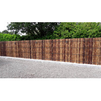 Bambuszaun in dunkler Farbe, der als Sichtschutz dient. Die Zaunelemente sind in gleichmäßigen Abständen angeordnet und bieten eine natürliche, ästhetische Lösung für die Abgrenzung eines Außenbereichs. Der Zaun ist auf einem stabilen, hellen Untergrund montiert und verleiht dem Garten eine moderne und zugleich natürliche Atmosphäre.