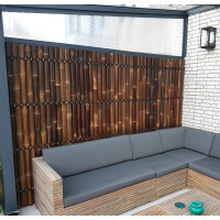 Ein modernes Outdoor-Sitzecke mit einem Sichtschutz aus Bambus, der als Zaunelement XXL SLIM in dunkler Farbe dient und eine natürliche, stilvolle Trennung bietet.