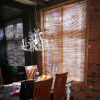 Bambusrollo als Sonnenschutz an einem Fenster, das den Raum vor direktem Sonnenlicht schützt und eine natürliche, warme Atmosphäre schafft.