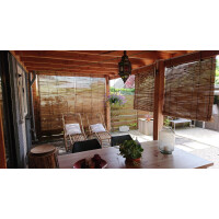 Bambusrollo Jalousie als Sichtschutz für Fenster und Türen, installiert an einer Holzpergola. Die naturfarbenen Bambuslamellen bieten eine stilvolle und umweltfreundliche Möglichkeit, Privatsphäre zu schaffen und Sonnenlicht zu filtern. Das Rollosystem misst 200x200 cm und passt ideal in moderne Outdoor-Bereiche.