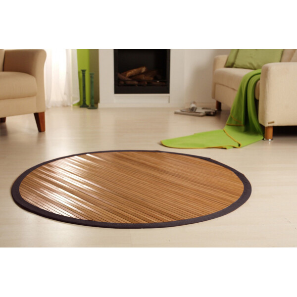 Runder Bambusteppich SENSUAL mit einem Durchmesser von 90 cm und 17 mm breiten Stegen. Der Teppich hat eine braune Bordüre und liegt auf einem hellen Boden in einem modernen Wohnzimmer.