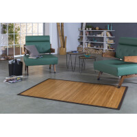 Große Bambusmatte mit dekorativer brauner Bordüre in modernem Wohnbereich mit grünen Sesseln und Holzmöbeln. Die Matte hat eine glatte Oberfläche mit gleichmäßigen Stegen und fügt sich harmonisch in das Interieur ein.