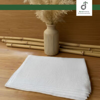 Eine Hand reinigt ein Bambusrohr mit einem weißen Pflegetuch. Der Boden besteht ebenfalls aus Bambus, im Hintergrund ein schlichter weißer Hintergrund. Oben rechts das DE-Commerce Logo.