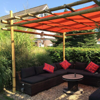 Bambuspergola mit stabiler Konstruktion und orangefarbenem Sonnenschutzdach, die eine gemütliche Sitzecke im Garten beschattet. Die Pergola besteht aus robusten Bambusstangen, die ein natürliches und stilvolles Ambiente schaffen.