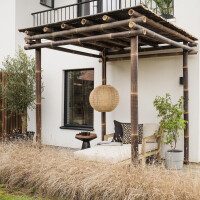 Holzige Bambus Pergola NIGRA mit vier robusten Stützen und einem stabilen Dach aus Bambusstäben, die einen schattigen Sitzbereich im Garten schafft. Maße: 400x300x300 cm.