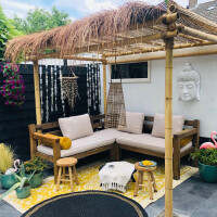 Bambuspergola mit Strohdach, Palmdach 200 x 70 cm, gemütlich eingerichtet mit Sitzkissen und Dekorationen, ideal für entspannte Sitzbereiche im Garten.