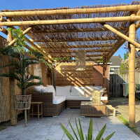 Elegante Bambus Pergola Guadua aus naturbelassenen Bambusstangen mit Strohdach, bietet einen stilvollen Schattenplatz für Gartenlounge und Outdoor-Möbel. Maße 400x400x300 cm.