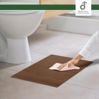 Eine Person reinigt einen quadratischen Bambus-Badteppich in Taupe vor einer weißen Toilette und einer Badewanne. Der Teppich hat ein geradliniges Design und misst 50 x 50 cm.