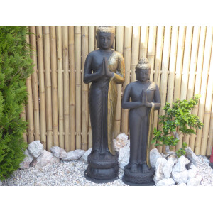 Zwei Buddha-Statuen stehen vor einem hohen Sichtschutz...
