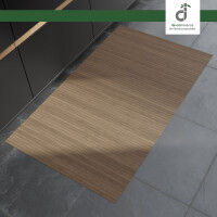 Rechteckiger, hellgrau-brauner Bambusläufer mit feinen Längsstreifen liegt auf einem grauen Steinboden vor modernen, dunklen Küchenunterschränken. Oben rechts befindet sich das DE-COmmerce Logo.