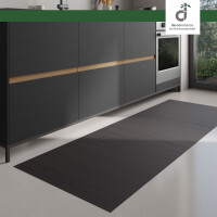 Moderner Küchenbereich mit dunklen Unterschränken und integriertem Backofen; auf dem hellen Boden liegt ein langer, rechteckiger Läufer aus dunklen schwarzbraunen Bambus. Rechts fällt Tageslicht durch ein großes Fenster ein. Oben rechts ist das DE-COmmerce Logo.