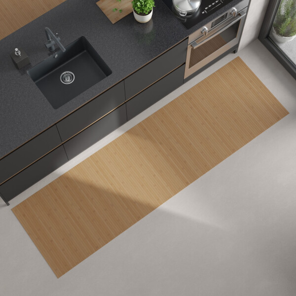 Moderne Küchenansicht von oben mit dunkler Arbeitsplatte, eingebautem schwarzen Spülbecken und Herd; auf dem hellen Boden liegt ein langer, rechteckiger Bambus-Küchenläufer in einem warmen Gelb mit Braunanteil.