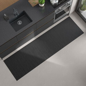 Moderne Küchenansicht von oben mit dunkler Arbeitsplatte, eingebautem schwarzen Spülbecken und Herd; auf dem hellen Boden liegt ein langer, rechteckiger, bläulich grauer Bambus-Küchenläufer.