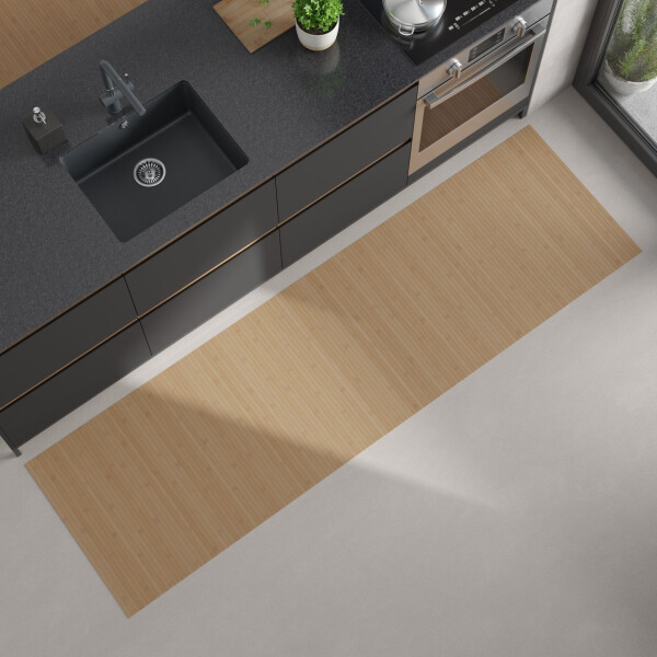 Moderne Küchenansicht von oben mit dunkler Arbeitsplatte, eingebautem schwarzen Spülbecken und Herd; auf dem hellen Boden liegt ein langer, rechteckiger, heller Bambus-Küchenläufer.