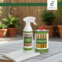 Pflegeset für Bambus steht auf einem Holztisch im Garten: Eine Sprühflasche Bamboo Cleaner, eine Dose Bamboo Care und fünf weiße Pflegetücher. Im Hintergrund stehen grüne Pflanzen in Blumen-Töpfen vor einem Bambuszaun. Oben rechts ist das DE-COmmerce Logo.