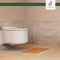 Modernes Badezimmer mit hellen Fliesen und einer Wandtoilette. Vor der Toilette liegt eine Bambus-Badeteppich, die aus kleinen Quadraten besteht. Oben rechts in der Ecke ist das DE-COmmerce Logo.