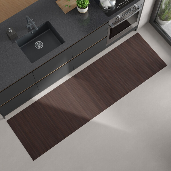 Moderne Küchenansicht von oben mit dunkler Arbeitsplatte, eingebautem schwarzen Spülbecken und Herd; auf dem hellen Boden liegt ein langer, rechteckiger Bambus-Küchenläufer in einem mittelbraun mit Kaffeeton.