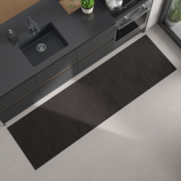 Moderne Küchenansicht von oben mit dunkler Arbeitsplatte, eingebautem schwarzen Spülbecken und Herd; auf dem hellen Boden liegt ein langer, rechteckiger Bambus-Küchenläufer in einem dunklen schwarzbraun.