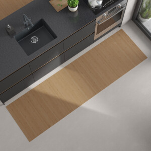 Moderne Küchenansicht von oben mit dunkler Arbeitsplatte, eingebautem schwarzen Spülbecken und Herd; auf dem hellen Boden liegt ein langer, rechteckiger, hellbeiger Bambus-Küchenläufer.