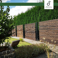 Moderner Garten mit dunklen Bambus-Windschutz an Metallpfosten, Holzsteg und Rasenfläche, im Hintergrund eine hohe grüne Hecke unter blauem Himmel, oben rechts das DE-COmmerce Logo.