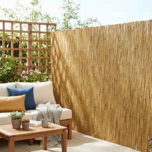 Helle Terrasse mit Schilf-Sichtschutzmatte entlang der...