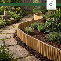 Flexible Bambus-Beeteinfassung als geschwungene Rasenkante, die eine grüne Rasenfläche mit Rasenmäher sauber von einem Gartenbeet mit Rindenmulch, Buchsbaum und Funkien trennt, oben rechts das DE-COmmerce Logo.