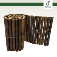 Dunkelbraune Bambus-Beeteinfassung, die ein mit Stauden und Kräutern bepflanztes Beet mit dunklem Mulch umrahmt. Im Hintergrund ist ein moosbewachsener Stein zu sehen, oben rechts das DE-COmmerce Logo.