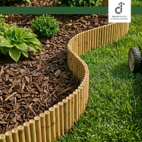 Flexible Bambus-Beeteinfassung als geschwungene Rasenkante, die eine grüne Rasenfläche mit Rasenmäher sauber von einem Gartenbeet mit Rindenmulch, Buchsbaum und Funkien trennt, oben rechts das DE-COmmerce Logo.