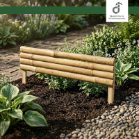 Blumenbeet im Garten mit Bambus-Beetumrandung, gefüllt mit Mulch und verschiedenen Pflanzen; kleine Pflanzschilder stecken in der Erde, daneben liegen einzelne Elemente der Beetumrandung auf dem Rasen, oben rechts das DE-Commerce Logo.