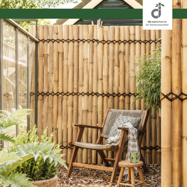 Sitzecke mit einem Sichtschutzelelement aus vertikal gebundenen Bambusspalten; davor steht ein Holzstuhl mit geflochtener Sitzfläche, umgeben von grünen Pflanzen; oben rechts das DE-COmmerce Logo.