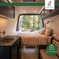 Gemütlicher Campervan mit hellem Bambus-Wand- und Deckenbelag, Doppelbett und kompakter Küche; durch die geöffneten Hecktüren fällt der Blick in einen grünen Wald. Eine Grafik weist auf das geringe Gewicht des Wandbelags von ca. 1,50 kg/m² hin, oben rechts das DE-COmmerce Logo.