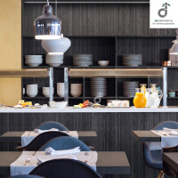 Modern eingerichteter Restaurant-/ Bistrobereich mit stahlgrauem Bambus-Wandbelag, offenen Regalen mit Geschirr, Buffettheke mit Getränken und Speisen sowie gedeckten Holztischen und dunkelblauen Stühlen, oben rechts ist das DE-COmmerce Logo.