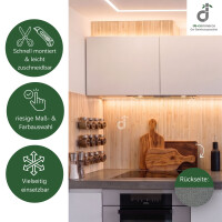 Bambus-Wandbelag in hellem Bambuston als stilvolle Wandgestaltung in einer modernen weißen Küche. Die natürliche Bambusstruktur schafft eine warme und wohnliche Atmosphäre. Das Produktbild zeigt zudem die schnelle und einfache Montage, leichte Zuschneidbarkeit, große Maß- und Farbauswahl, vielseitigen Einsatzmöglichkeiten sowie die rutschfeste Rückseite des Wandbelags „Vlies mit Dots“; oben rechts das DE-COmmerce Logo.