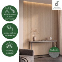 Bambus- Wandbelag in hellem Bambuston als natürliche und stilvolle Wandgestaltung eines modernen Wohnbereichs mit Sessel, Konsolentisch und dezenter Dekoration. Das Produktbild zeigt die einfache und schnelle Montage sowie die leichte Zuschneidbarkeit, eine große Auswahl an Maßen und Farben und die vielseitigen Einsatzmöglichkeiten. Zusätzlich ist die rutschfeste Rückseite des Wandbelags „Vlies mit Dots“ abgebildet; oben rechts das DE-COmmerce Logo.